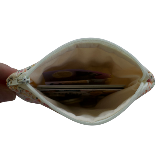 Small pouch held open by a hand, revealing coins inside on a white background