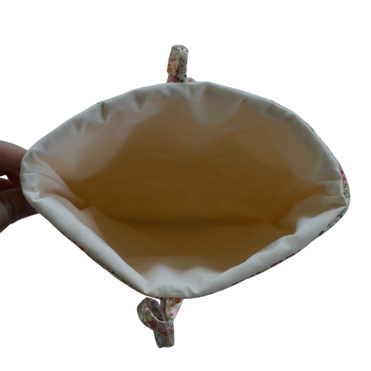 Hand holding a beige fabric pouch with a white background for books