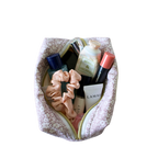 A top-down view of a floral patterned cosmetic pouch filled with various beauty products. Small makeup bag. Handmade small pouch. Quilted handmade bag