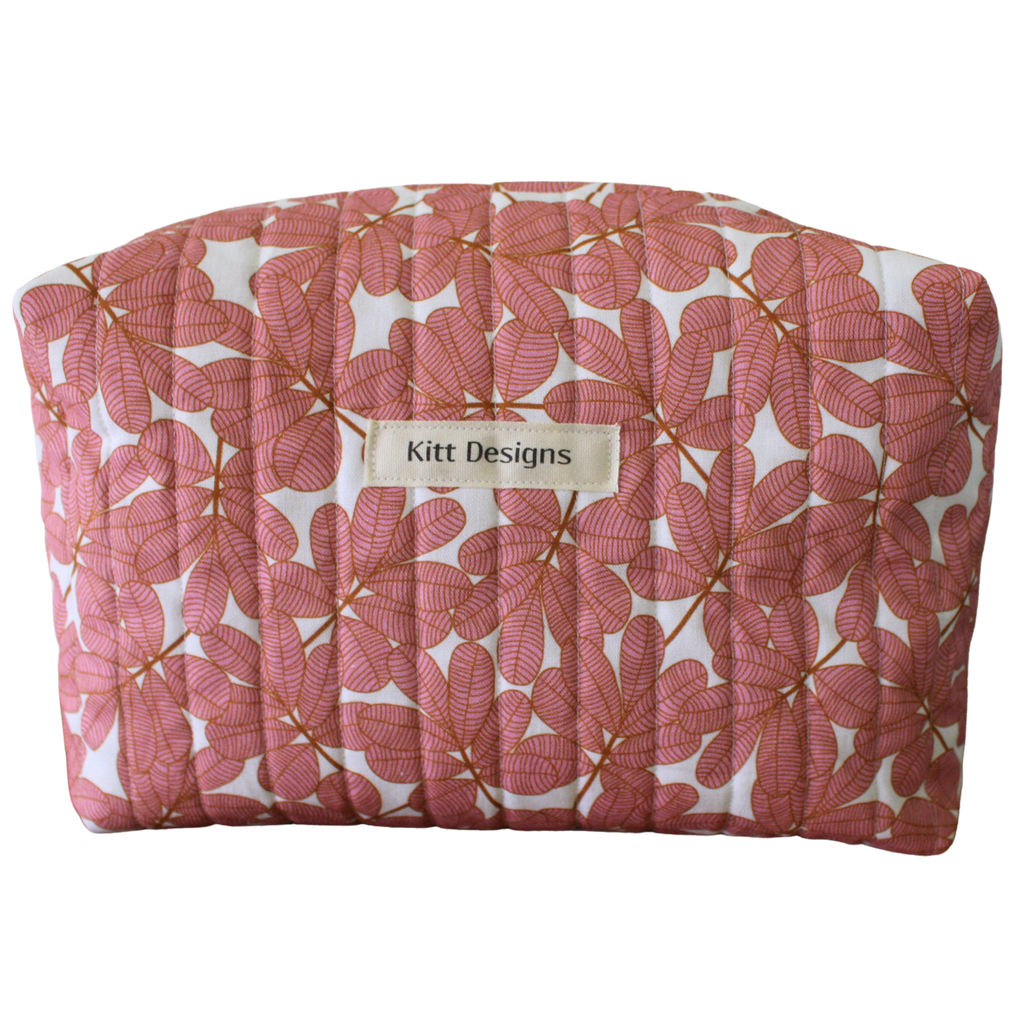 Pink floral-patterned pouch with 'Kitt Designs' label travel pouch