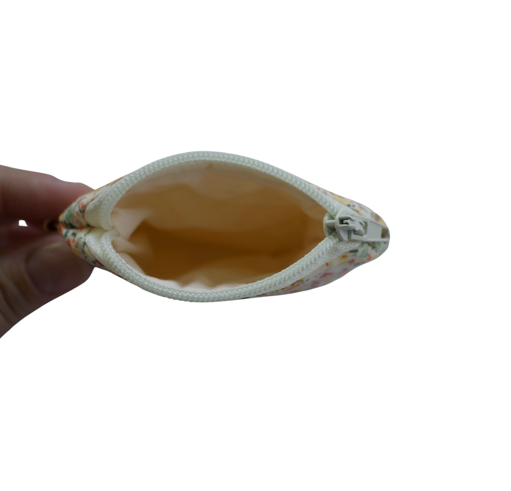 Hand holding a beige pouch with floral patterns on a white background