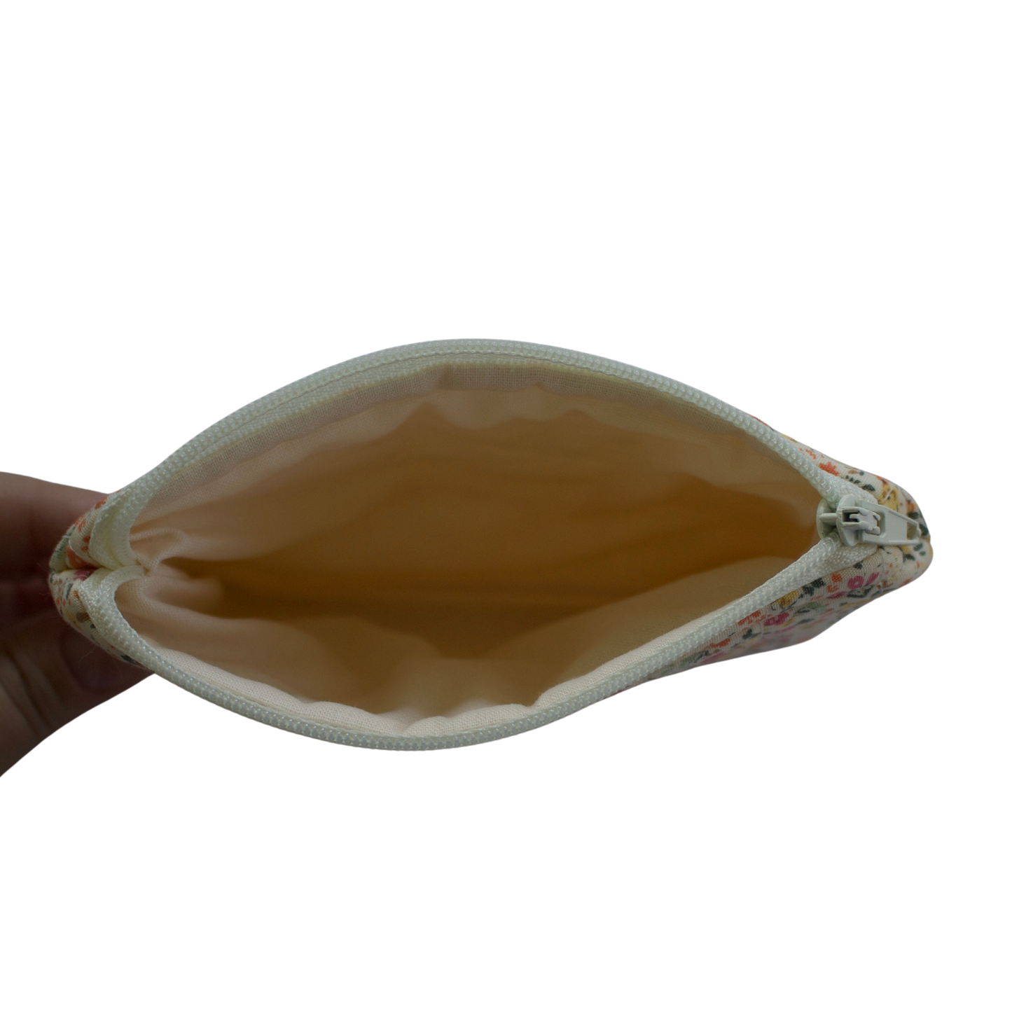 Hand holding a beige pouch with floral edge on a white background