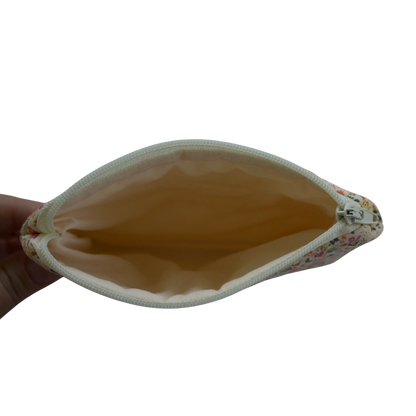 Hand holding a beige pouch with floral edge on a white background