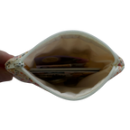 Small pouch held open by a hand, revealing coins inside on a white background