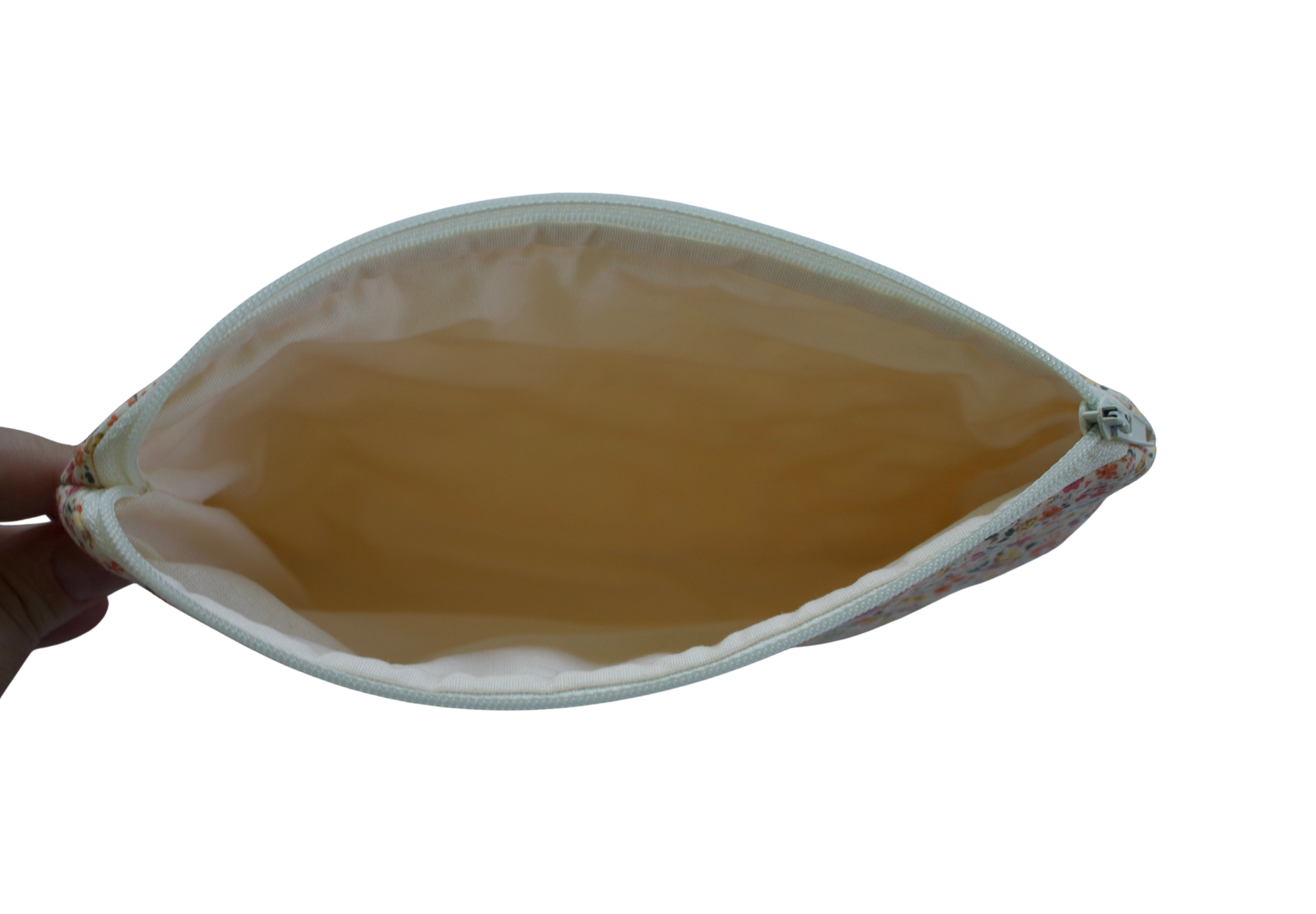 Hand holding a leaf-shaped pouch with a yellowish-brown interior on a white background zipper pouch