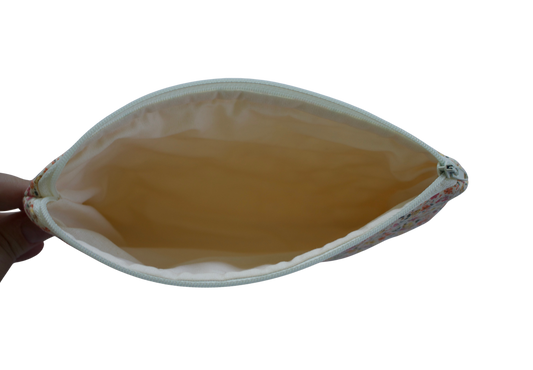 Hand holding a leaf-shaped pouch with a yellowish-brown interior on a white background zipper pouch