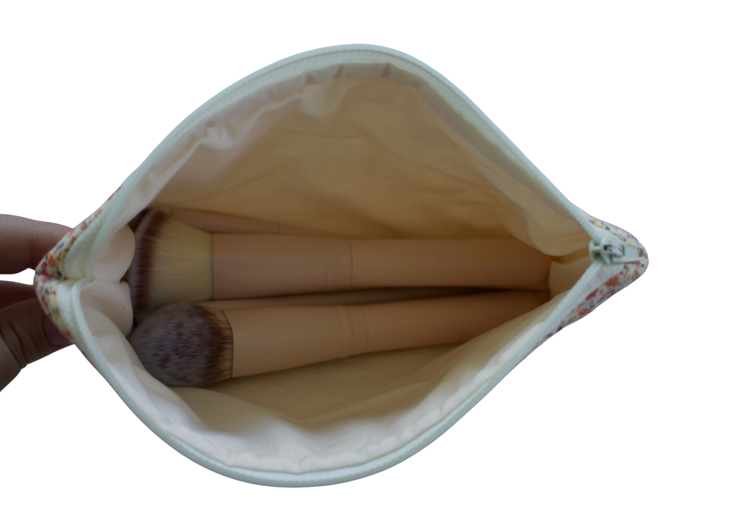 Makeup brushes in a white pouch held by a hand on a white background zipper pouch