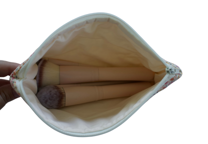 Makeup brushes in a white pouch held by a hand on a white background zipper pouch
