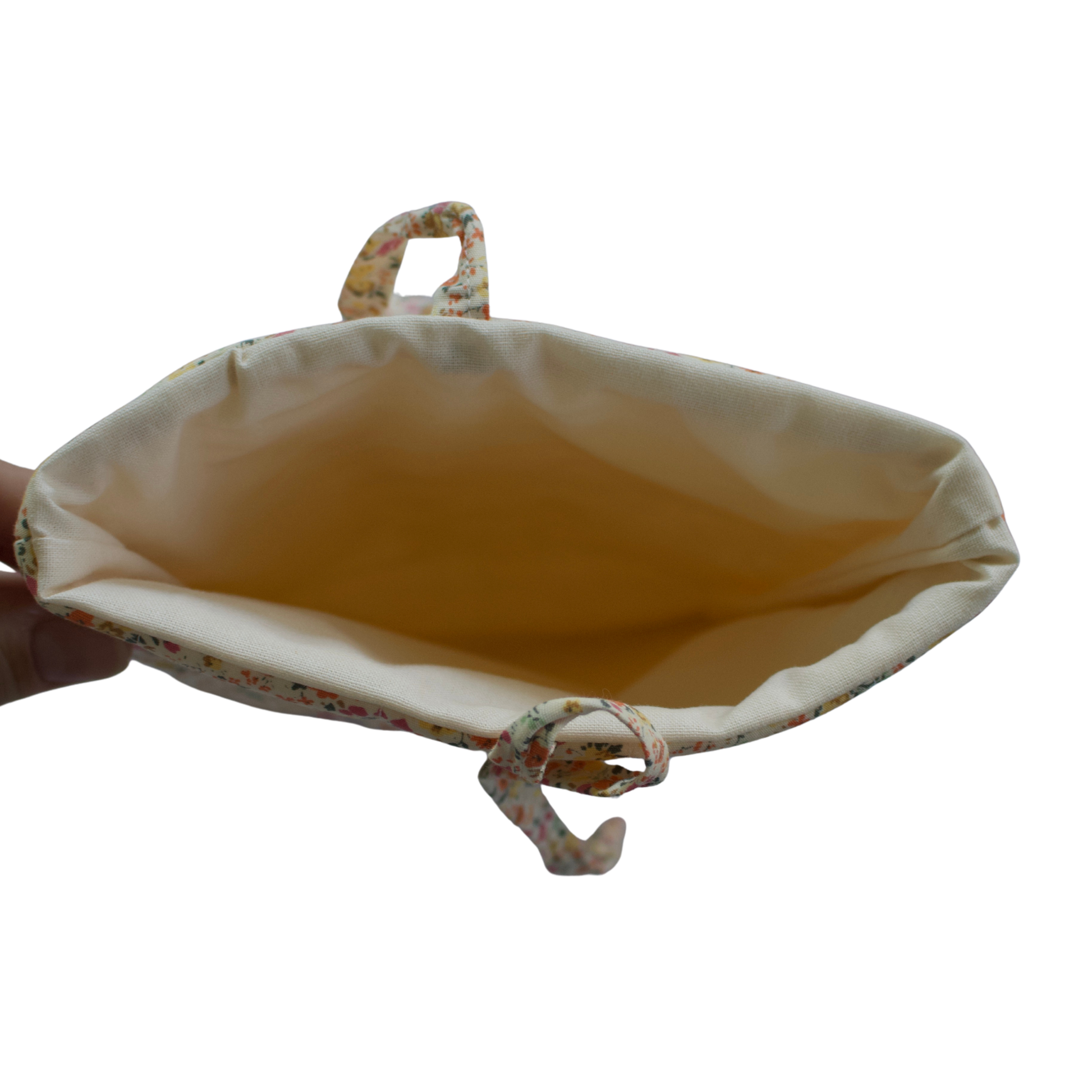 Hand holding a beige pouch with a white background small book sleeve