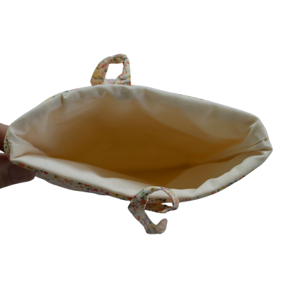 Hand holding a beige pouch with a white background small book sleeve