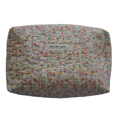 Floral-patterned cushion with 'Kitt Designs' label on a white background travel pouch