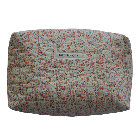 Floral-patterned cushion with 'Kitt Designs' label on a white background travel pouch
