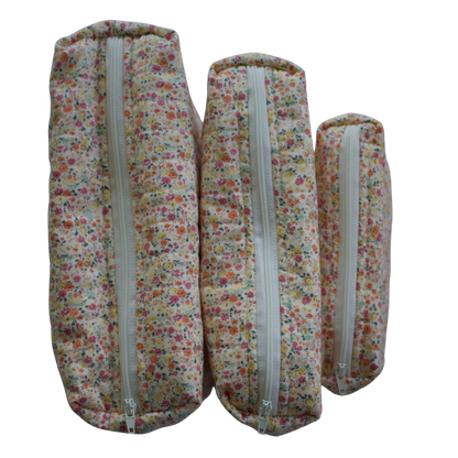 Three floral-patterned fabric rolls with zippers on a white background