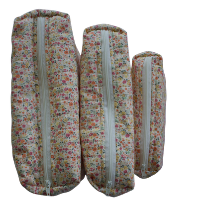 Three floral-patterned fabric rolls with zippers on a white background