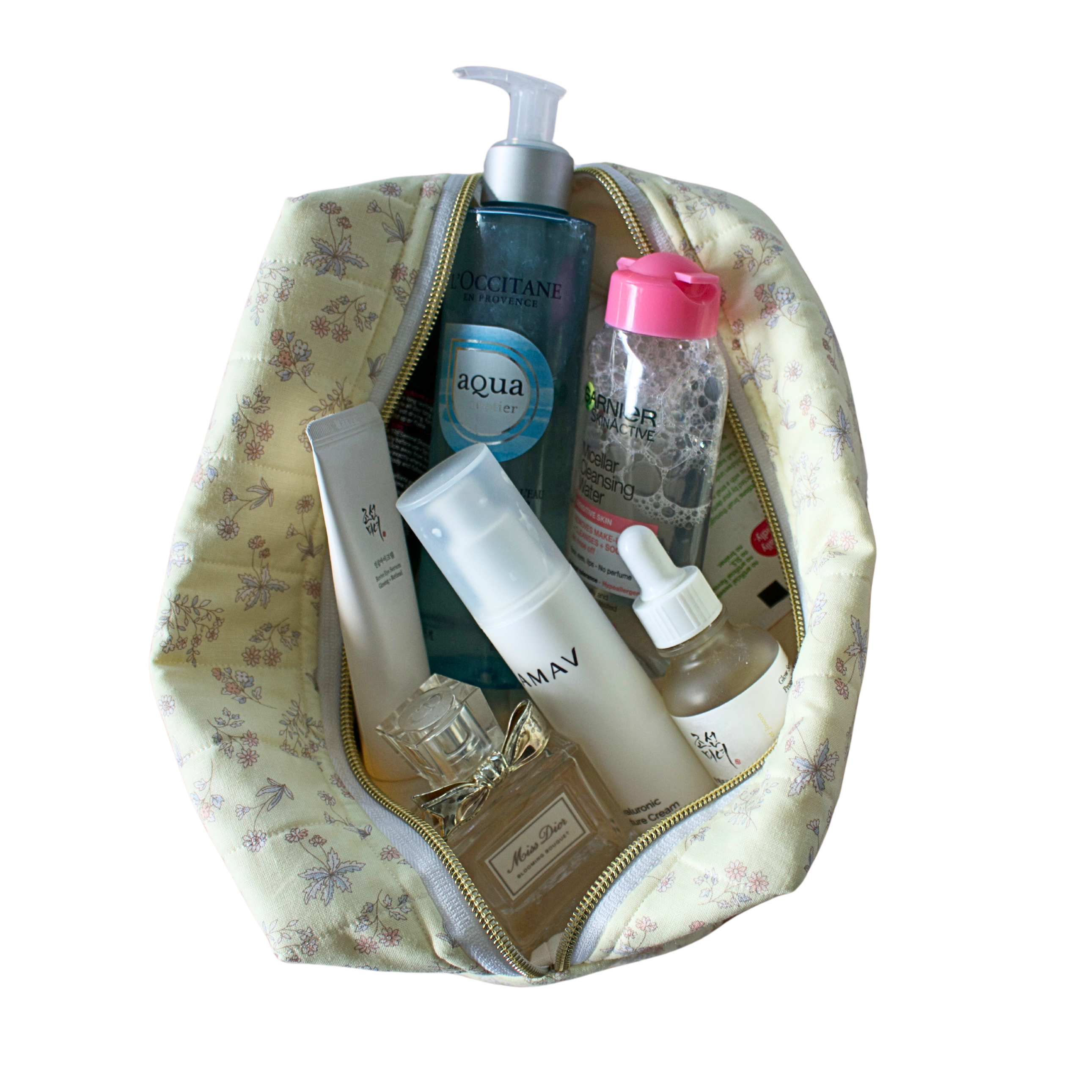 A yellow floral makeup bag filled with various skincare and beauty products. Handmade cosmetics pouch. Toiletry bag. handmade quilted pouch. cosmetic bag.