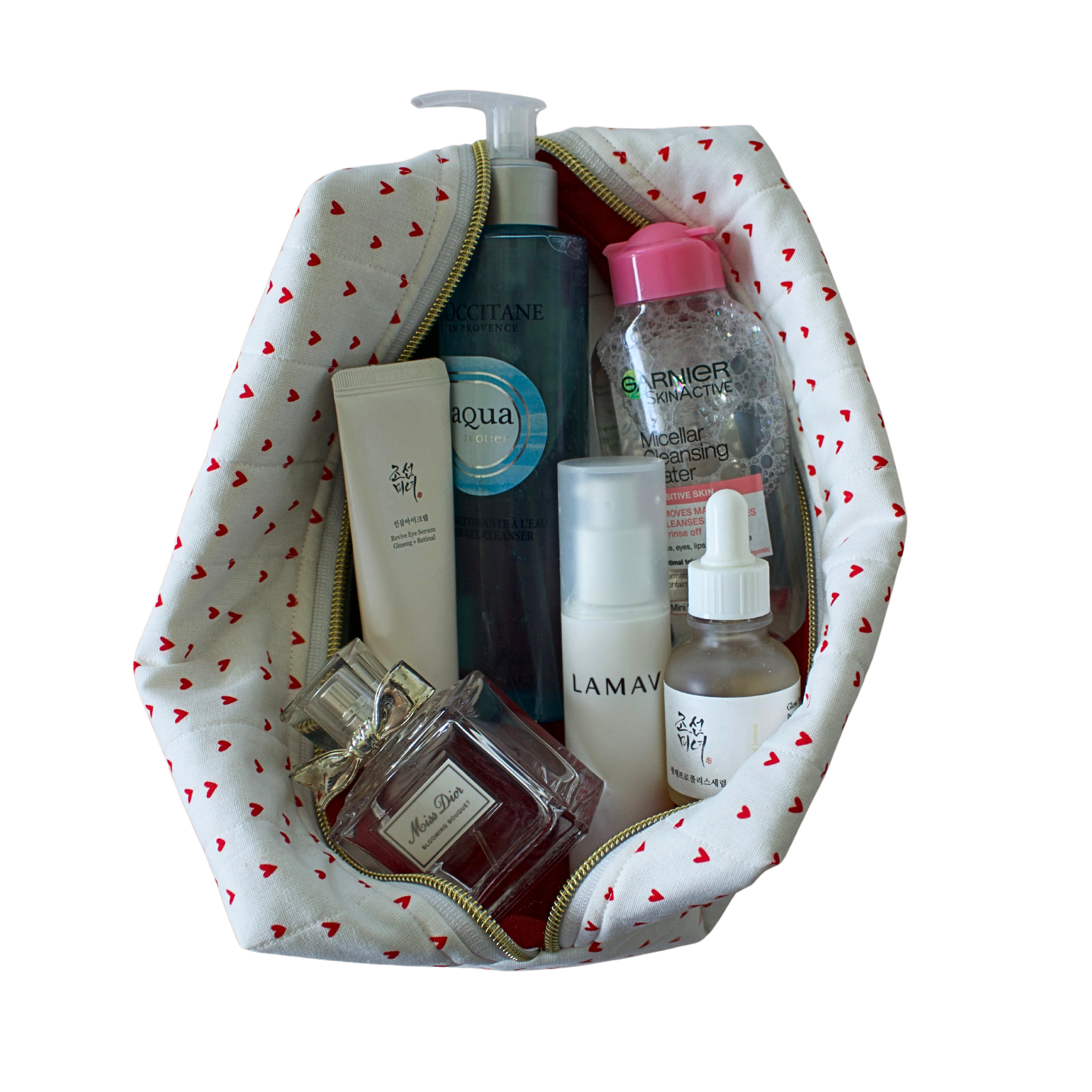 A white cosmetic bag with a red heart pattern, shown open and filled with various skincare and perfume products on a solid white background. handmade pouch. handmade cosmetic pouch. Handmade quilted pouch. Handmade bag
