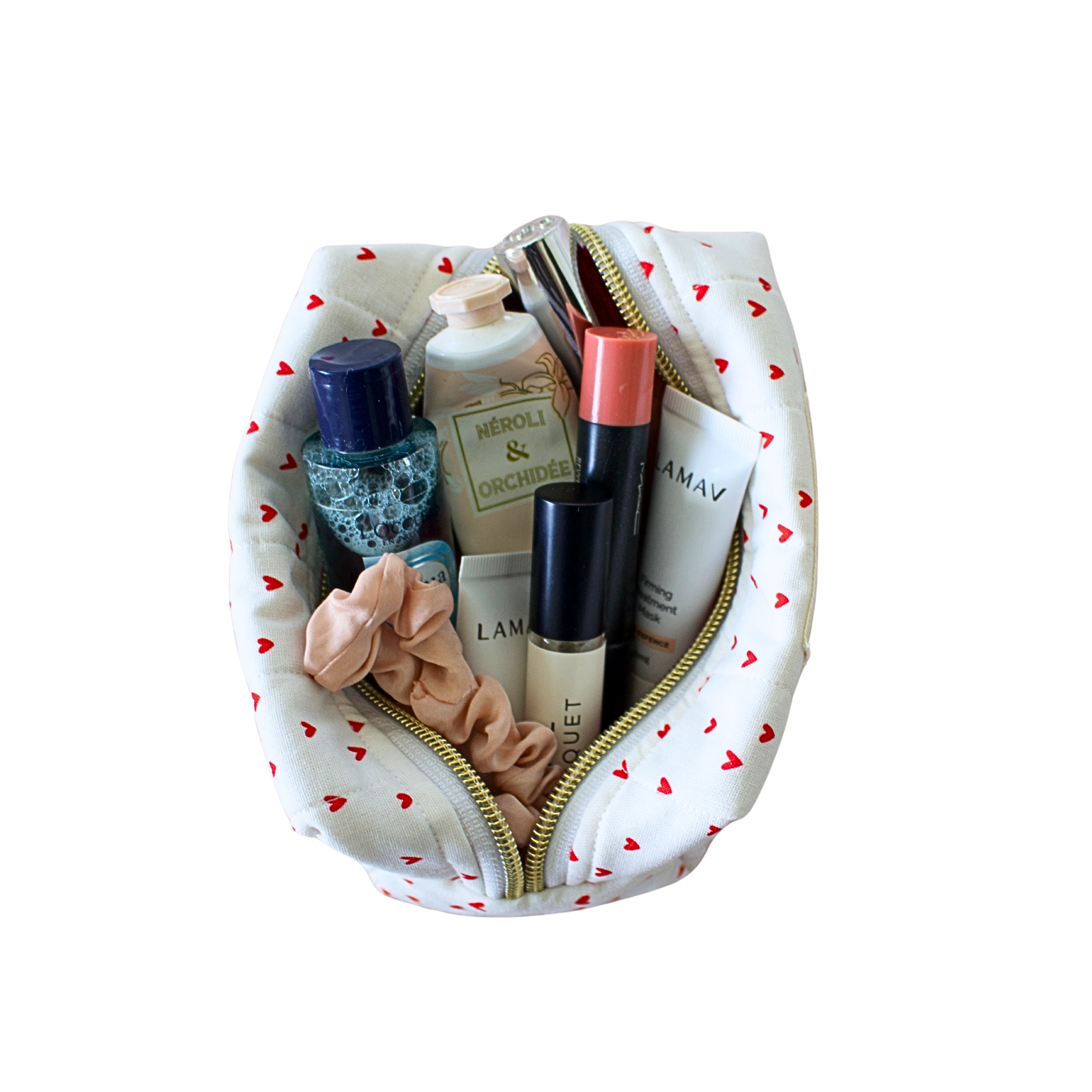 A white cosmetic pouch with a red heart pattern and gold zipper, shown open with various beauty products inside on a plain white background. Handmade small pouch. Handmade quilted pouch. Small bag. 