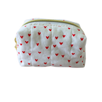 A small quilted fabric pouch with a white background and a pattern of small red hearts, featuring a gold zipper.